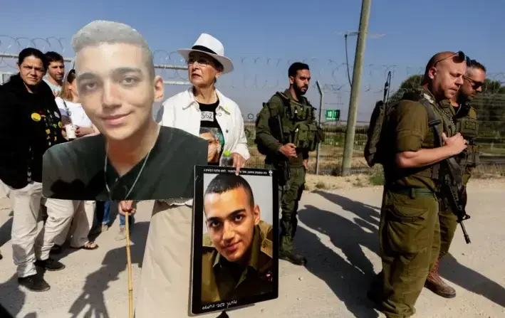 Varda Ben Baruch sostiene fotos de su nieto, el rehén israelí-estadounidense Edan Alexander, mientras camina cerca de soldados israelíes durante una manifestación de familiares de rehenes retenidos en la Franja de Gaza, en Nir Oz, Israel, el 20 de abril de 2025. (Amir Levy/Getty Images)

