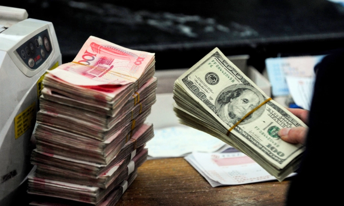 
Un empleado de un banco chino se prepara para contar billetes de dólar estadounidense y un fajo de billetes de 100 yuanes en un banco de Hefei, provincia de Anhui, China, el 9 de marzo de 2010. STR/AFP a través de Getty Images

