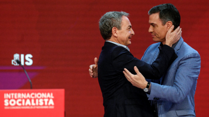 El presidente del Gobierno español, Pedro Sánchez (d), abraza al expresidente del Gobierno español, José Luis Rodríguez Zapatero, durante el XXVI Congreso de la Internacional Socialista en Madrid, el 27 de noviembre de 2022. (OSCAR DEL POZO/AFP vía Getty Images)